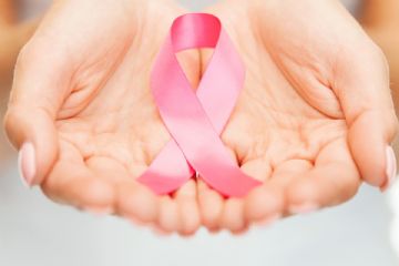 mani di donna che tengono al suo interno un nastro rosa incrociato