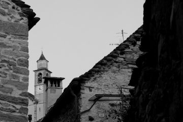 Immagine in bianco e nero dei tetti delle case antiche e del campanile di Oira