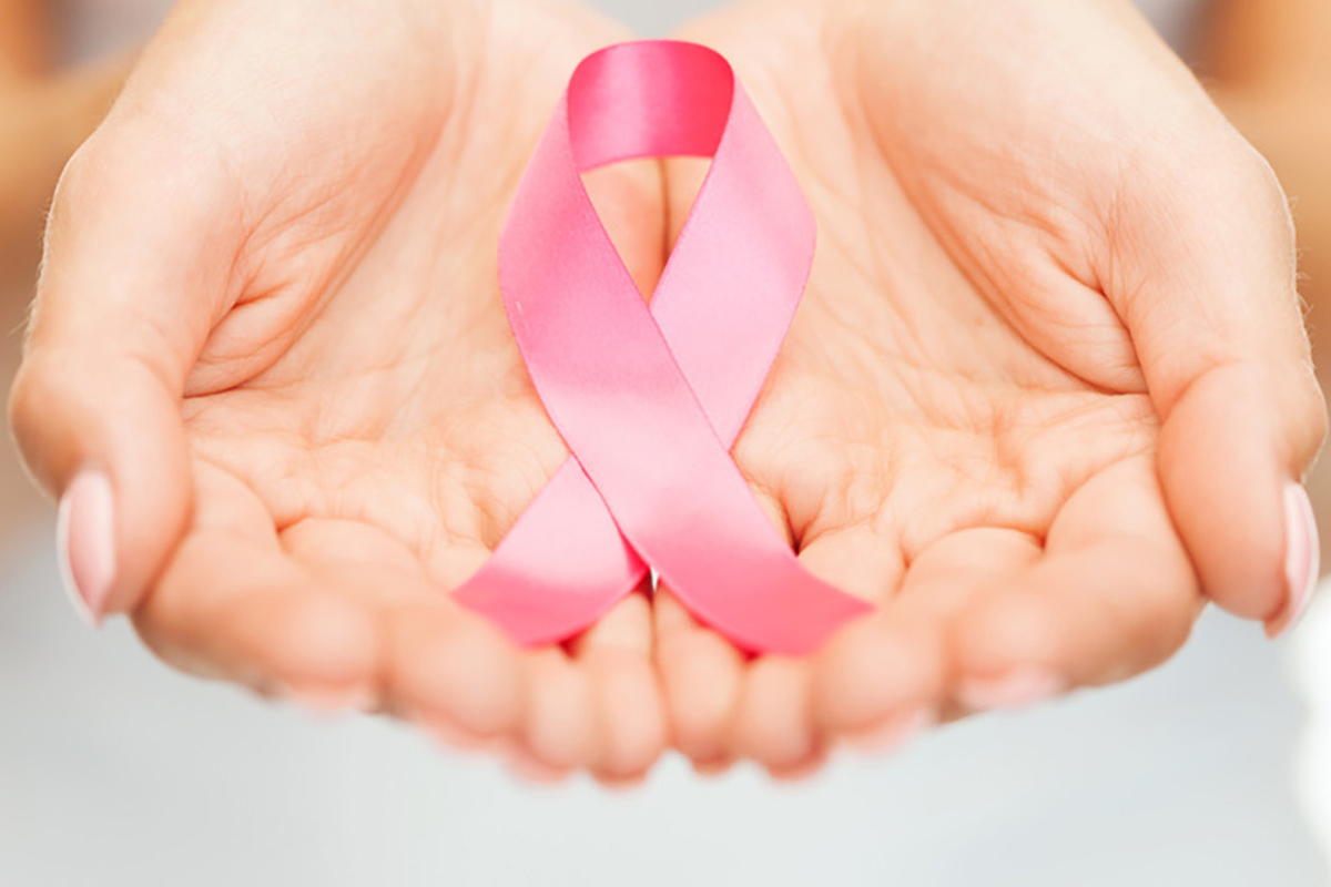 mani di donna che tengono al suo interno un nastro rosa incrociato