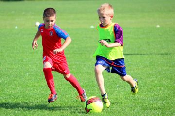 Foto con due bambini che giocano a calcio in un campo