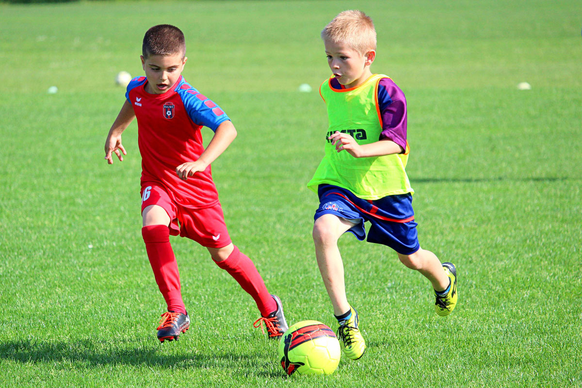 Foto con due bambini che giocano a calcio in un campo